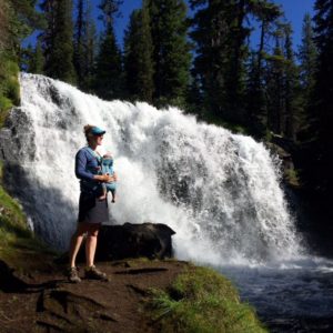 Mom holding baby in front of waterfall