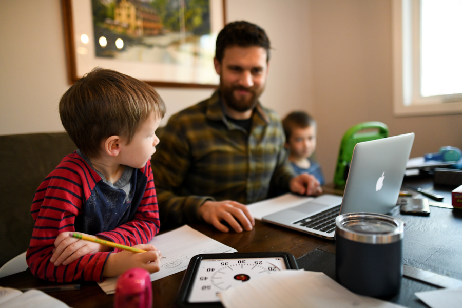 father at table with computer and two young sons - tips for homeschooling