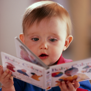 Young toddler looking at a book. Keep your baby entertained with treasure baskets that include books.
