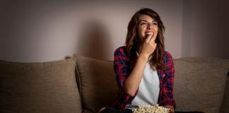 Woman eating popcorn on couch - best shows you aren't watching
