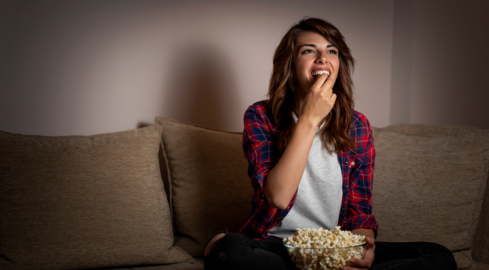Woman eating popcorn on couch - best shows you aren't watching