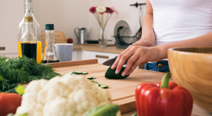 woman's hands cutting a cucumber on a cutting board - meal delivery services