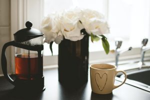Spring cleaning mug with heart, tea pot, and vase of flowers