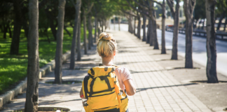 girl walking down road with yellow backpack