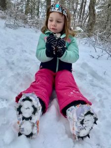 little girl enjoys a snowy hike with cleats