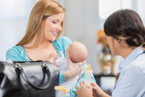 Mother holds baby and speaks with a lactation professional