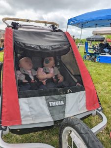 Twin toddlers sleep in a running stroller during a camping trip