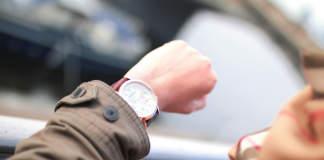 The image shows a left arm raised of an adult woman, wearing a watch. Implies they are checking the time.