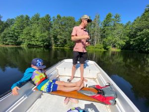 Father fishes on boat while son lounges