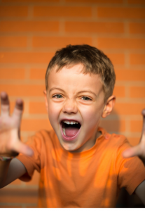 Child in orange shirt against orange background, imitating a lion's roar, like one of the breathing exercises for kids