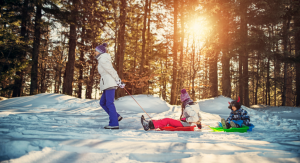 parent pulls kids on sleds in snow