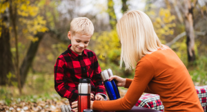 mom and kid drink hot beverage outside