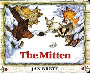 The Mitten Book Cover - Lone mitten in snow with several woodland animals surrounding it. 