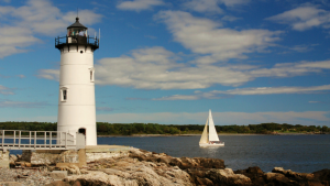 lighthouse with sailing ship going by