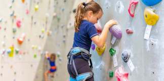 girl climbing on rock climbing wall in gym