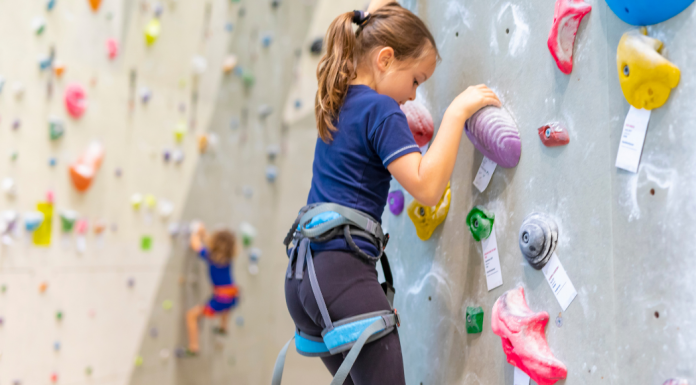 girl climbing on rock climbing wall in gym