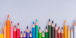 row of colored pencils with light grey background