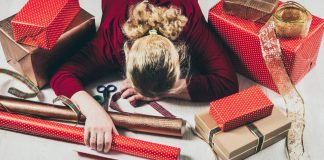 overwhelmed woman among wrapping paper