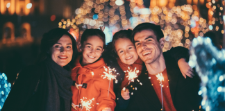 family smiles in winter on a street with sparklers