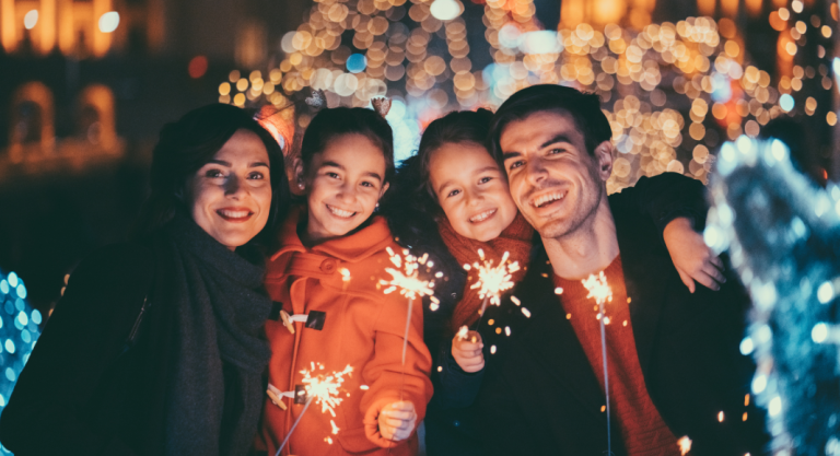 family smiles in winter on a street with sparklers